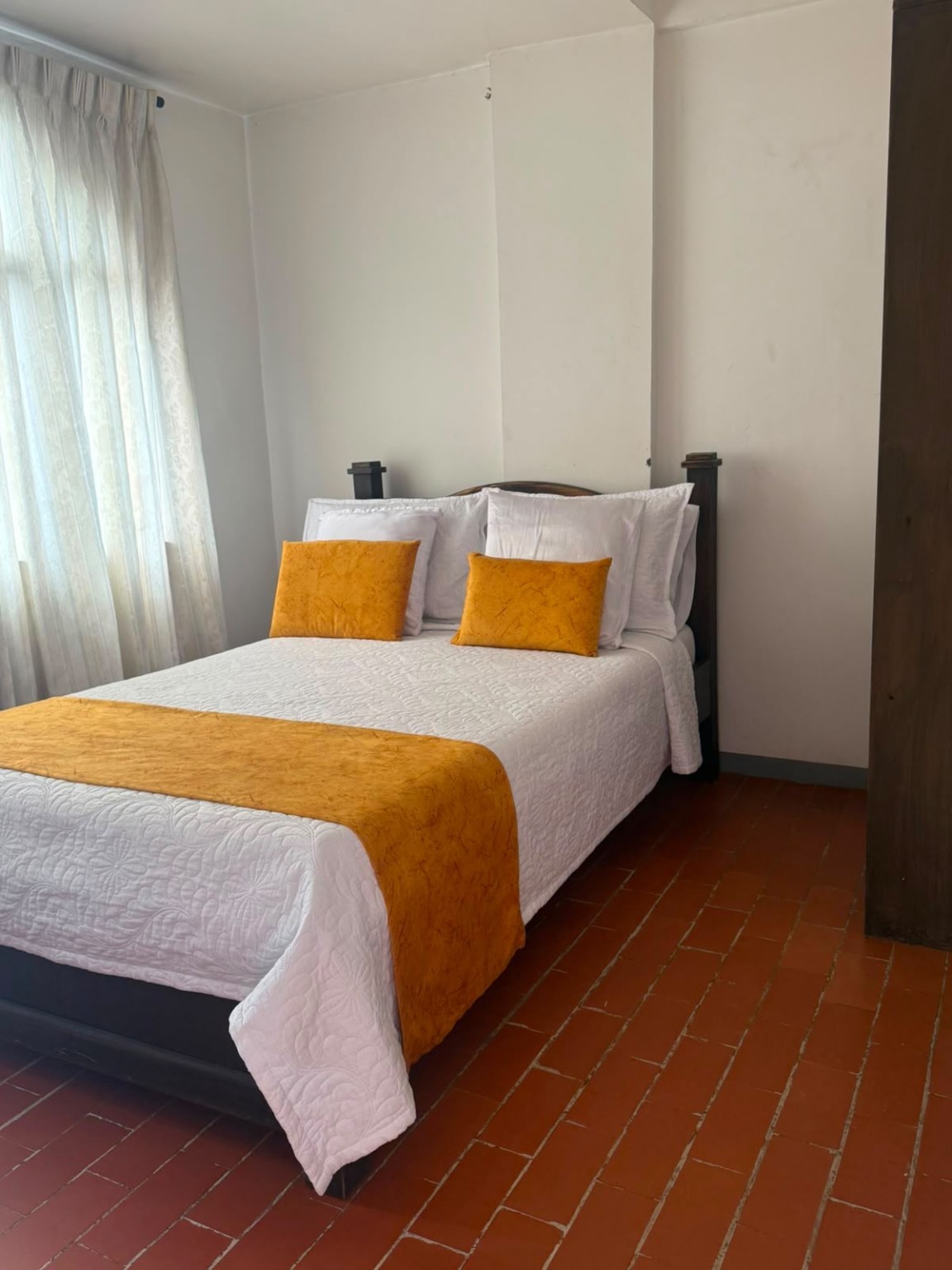 Habitación de Maraná con cama doble, ropa de cama blanca y detalles dorados